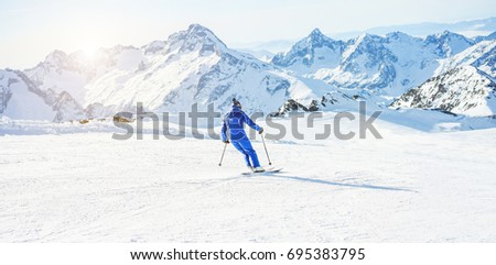 Young athlete skiing in Deux Alps french mountains on sunny day - Skier riding down for winter snow sport competition - Training and vacation concept - Focus on him - Warm filter  Royalty-Free Stock Photo #695383795