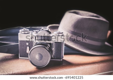 Adventure concept. Old film camera with vintage hat and umbrella on old brown suitcase. Vintage toned image