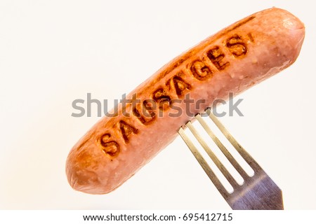 sausage with an inscription pinned on a fork, on a white background.