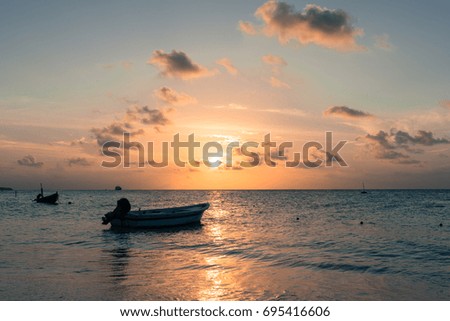 Horizontal picture from the beach of boat silhouette during sunset time with cloud sky at Maafushi in Maldives.