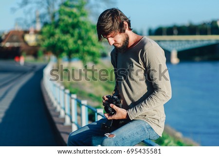 Fashionable man takes a photo with an old retro camera in the park