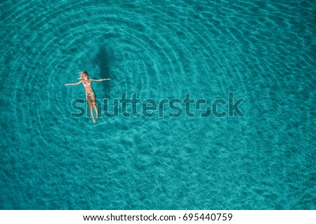 Aerial view of swimming woman in Blue Lagoon. Mediterranean sea in Oludeniz, Turkey. Summer seascape with girl, clear azure water, waves at sunrise. Transparent water.Top view from flying drone.Travel Royalty-Free Stock Photo #695440759