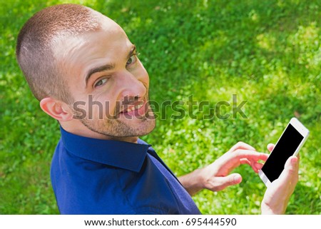man, using a smart phone, in the hands, background, with copy space, free space, for advertising, outdoors, park