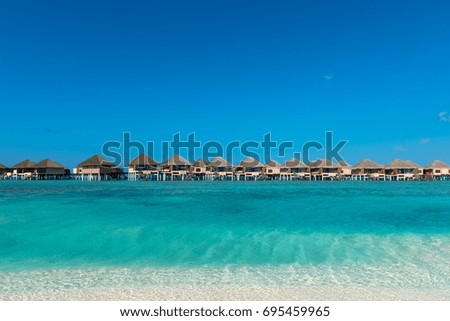 Horizontal picture of turquoise water with bungalows during a sunny day in Maldives