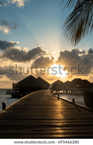 Vertical picture of yellow beautiful sunset  over bungalows with cloudy sky in Maldives.