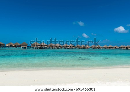 Panorama picture of turquoise water with bungalows during a sunny day in Maldives