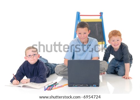Young boys casual dressed, doing homework on laptop.  White background, studio shot.