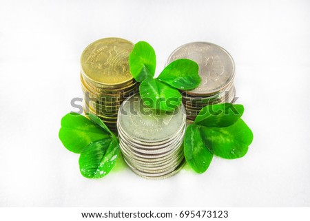 Stacks of Russian coins with clover leaves on a gray background with droplets of water. St.Patrick 's Day