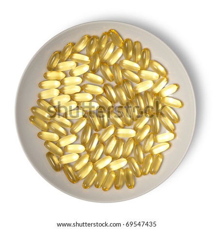 Gold medical capsules on plate isolated on white. Clipping path