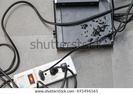 Electrical appliances and wires are wet on the floor.