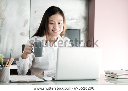 Young asian office woman working with laptop computer and holding coffee cup at desk office background, Office lifestyle concept
