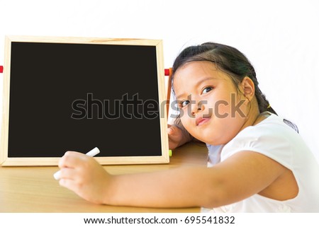 Portrait of little Asia Thai girl smart schoolchild writing at blackboard and looking at camera,use for art and painting education concept