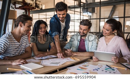 Beautiful young business people in casual clothes are discussing work and smiling at the conference in office Royalty-Free Stock Photo #695559904