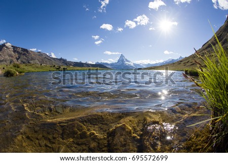 View to famous Mount Matterhorn from Stellisee lake, Zermatt, Switzerland. Sun sparkles reflect on water surface.
