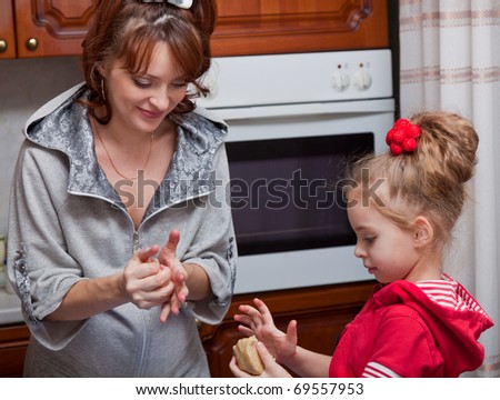 a mother with her daughter are cooking in the kitchen