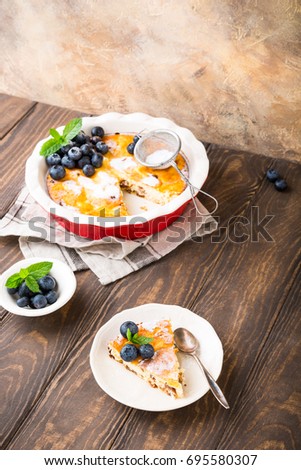 Piece of homemade gluten free cheesecake made from cottage cheese, decorated with blueberries and mint on wooden background. Healthy food concept with copy space.