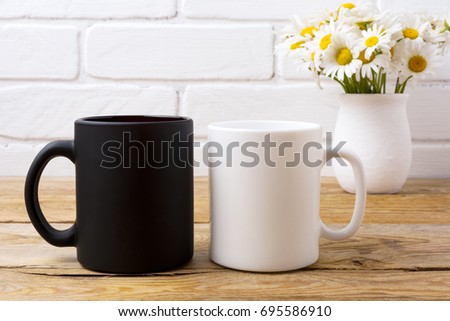 White and black coffee mug mockup with white field chamomile bouquet in handmade rustic vase.  Empty mug mock up for design promotion.   Royalty-Free Stock Photo #695586910