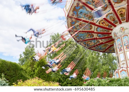 Children swinging on caroussel in theme park on weekend Royalty-Free Stock Photo #695630485