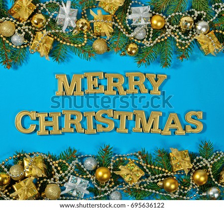 Merry Christmas golden text and spruce branch and Christmas decorations on a blue background