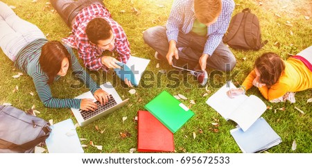 College students using laptop while doing homework at park Royalty-Free Stock Photo #695672533
