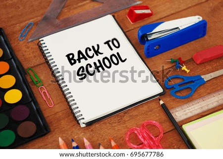 Back to school text on white background against school supplies on wooden table