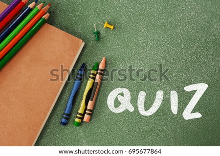 Quiz text against white background against high angle view of crayons and book
