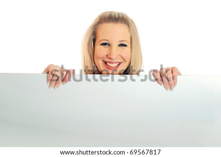 Portrait of an attractive smiling young woman peeping or looking over a white board against white background