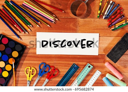 Discover text on white background against directly above shot of blank paper with school supplies