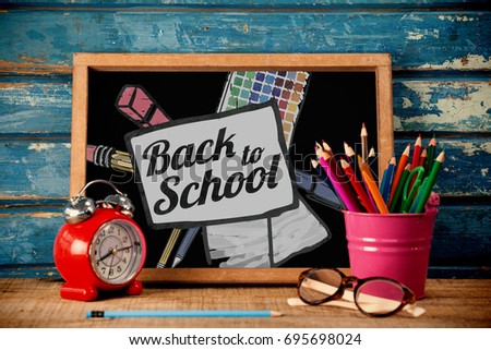 Back to school text on paper with pen against blackboard with alarm clock on table