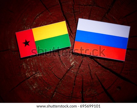 Guinea Bissau flag with Russian flag on a tree stump isolated