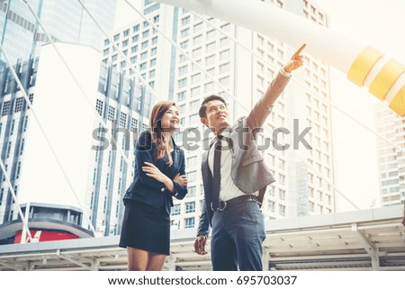 Young business man and woman outdoor pointing looking away while walking to office together.
