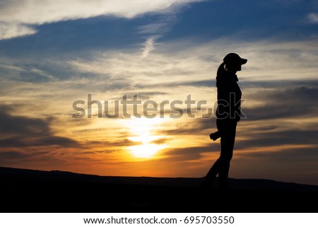 Silhouette Woman Photographing Landscape At Sunset. Female photographer holding a camera. 