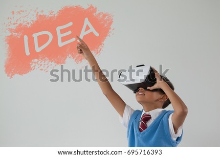 Digital composite image of idea text on black spray paint against schoolboy using virtual reality headset