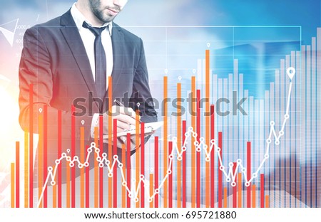Close up of a bearded young businessman with a planner standing in a city. There is a graph in front of him in the foreground. Toned image double exposure