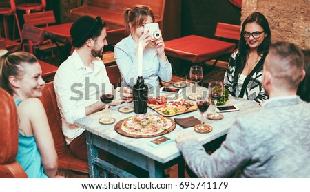 Happy friends enjoying appetizer in trendy vintage bar - Young people having fun shooting photos and drinking red wine - Youth and party concept - Focus camera and right girl - Retro camera filter
