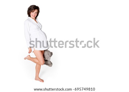 Pregnant woman holding soft toy. Pretty young woman carrying teddy bear. Free space for text.