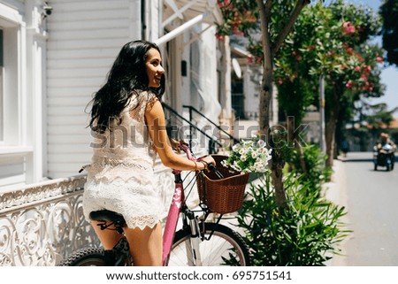 Eastern girl sitting on vintage bicycle with bucket of flowers