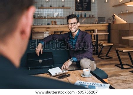 portrait of smiling businessman having meeting with colleague in cafe
