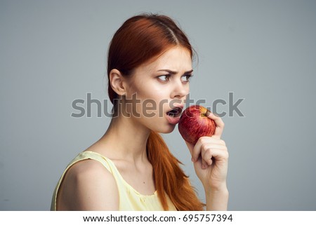 Young beautiful woman on a gray background holds an apple, portrait, emotions.