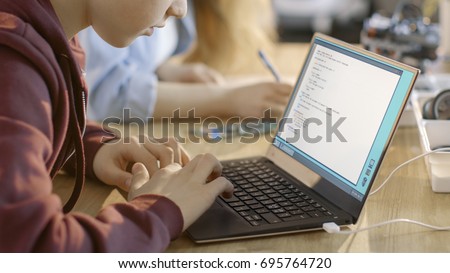 Smart Young Boy Works on a Laptop For His New Project in His Computer Science Class. Royalty-Free Stock Photo #695764720