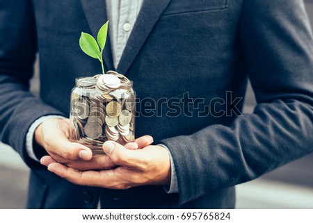 Businessman cover growing plant with coin money,Plant growing out of coins with filter effect retro vintage style,concept money growing and small tree in jar, economy concept