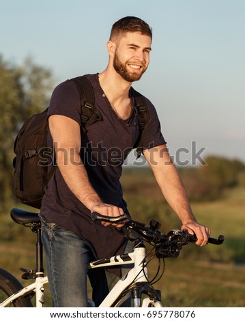 Young man Cyclist riding  bike in wood at sunset.
