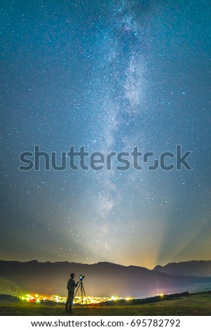 The man with a camera stand on the background of the starry sky. night time