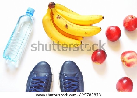 Bottle with clean drinking water, yellow bananas, red peaches and blue female sneakers. Flat lay stock photography. Proper eating and healthy lifestyle concept