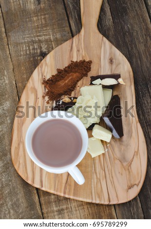 Cup of chocolate and pieces of chocolate on a kitchen table.