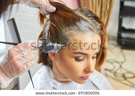 Beautician dying hair of woman. Girl in beauty salon. Royalty-Free Stock Photo #695806006