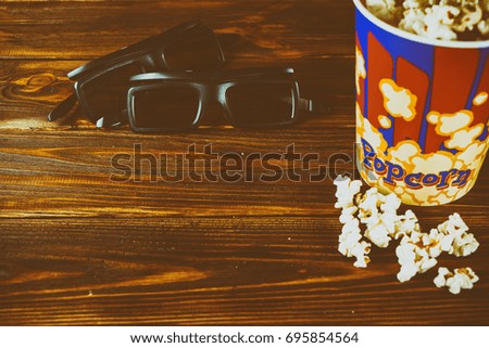 Popcorn and glasses for watching 3d movies on a wooden background. Toned photo