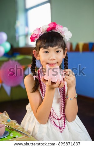 Portrait of cute girl holding toy teapot during birthday party at home
