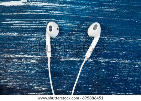 White little headphones on blue jeans wooden isolated background