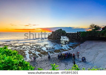 Tourist gathering taking a group photo at Batu Bolong Beach,Bali,Indonesia,with sunset sky background.